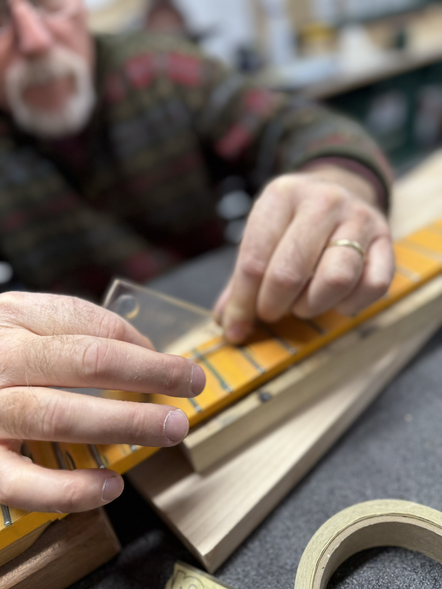 Hands checking fretwork on a guitar neck during a private workshop.
